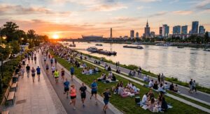 A cinematic high-angle shot of Vistula River boulevards at sunset, showing a mix of urban joggers an